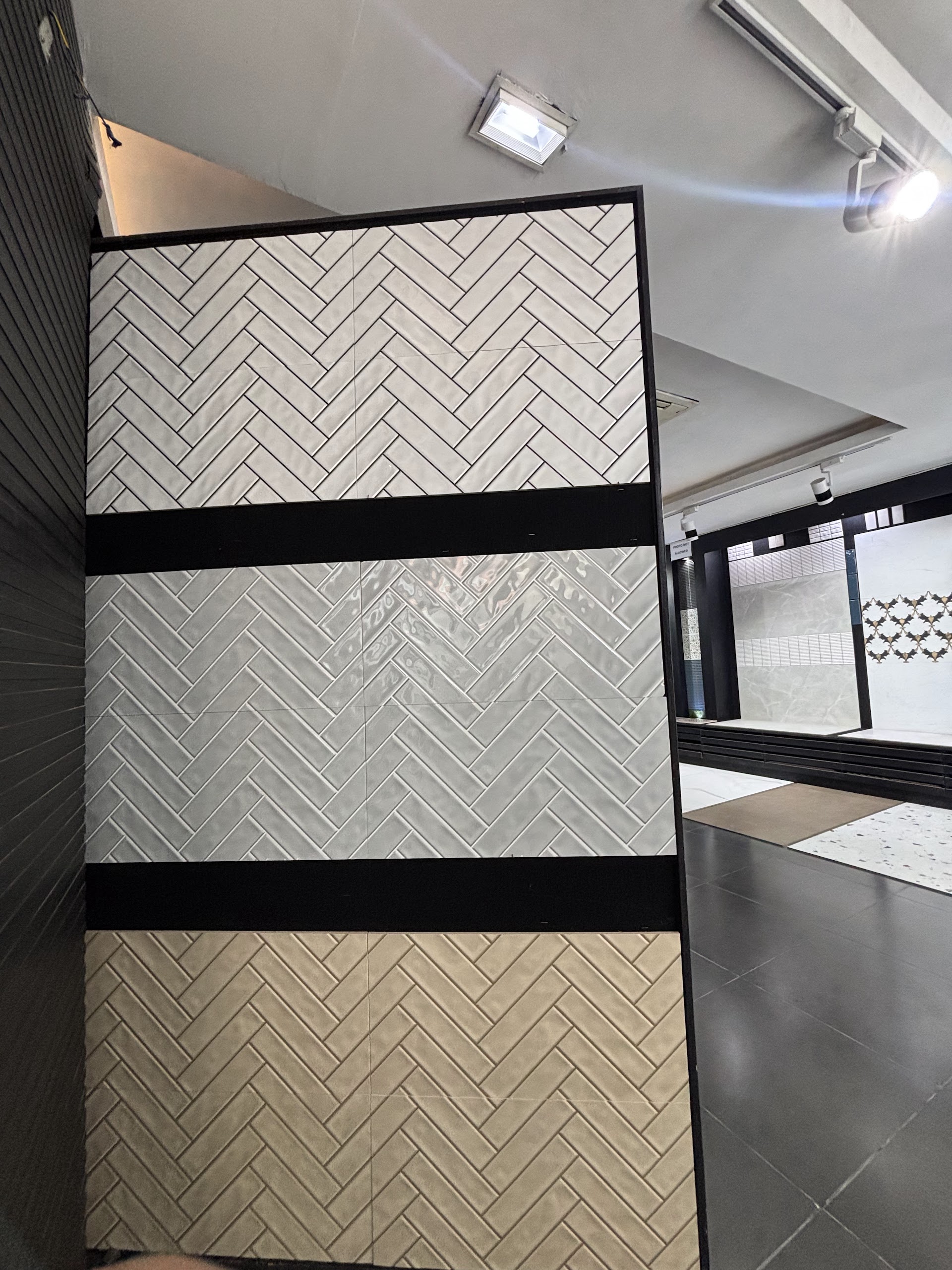 Three herringbone tile displays in pale, grey and warm neutral tones at the World of Tile showroom