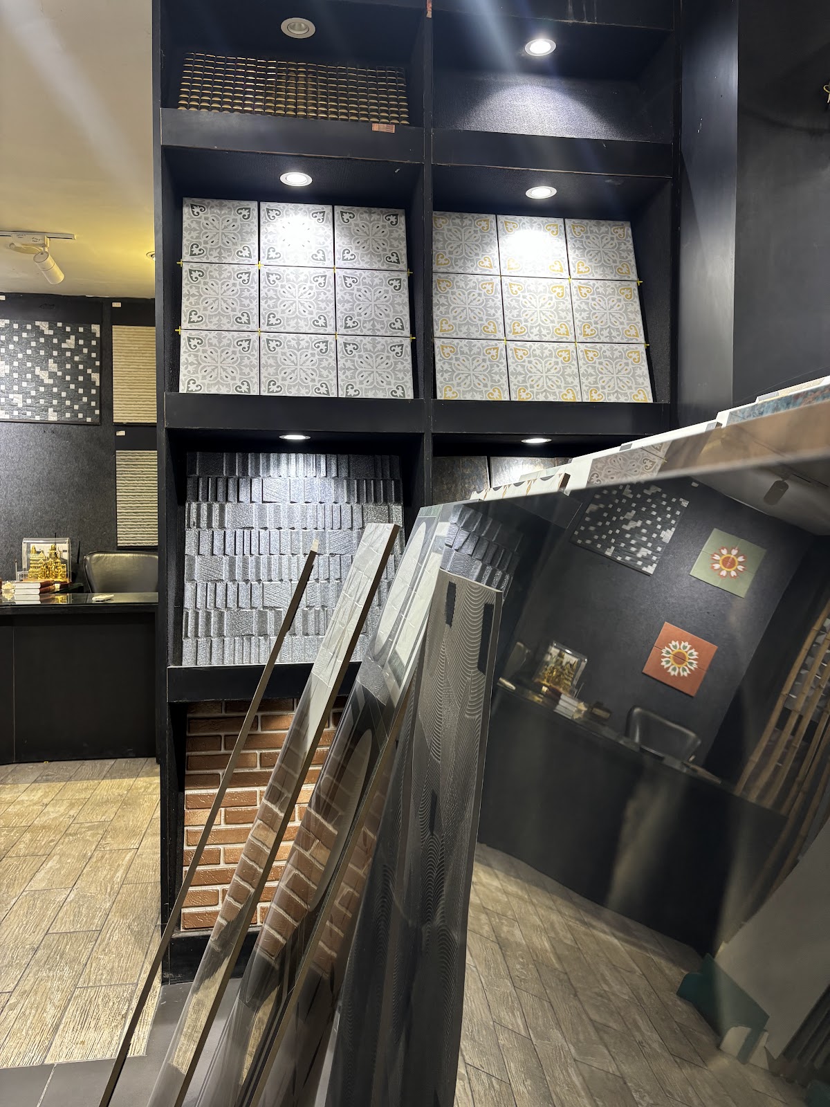 Angled tile display racks beneath illuminated patterned wall panels at World of Tile in Sector 9 Noida