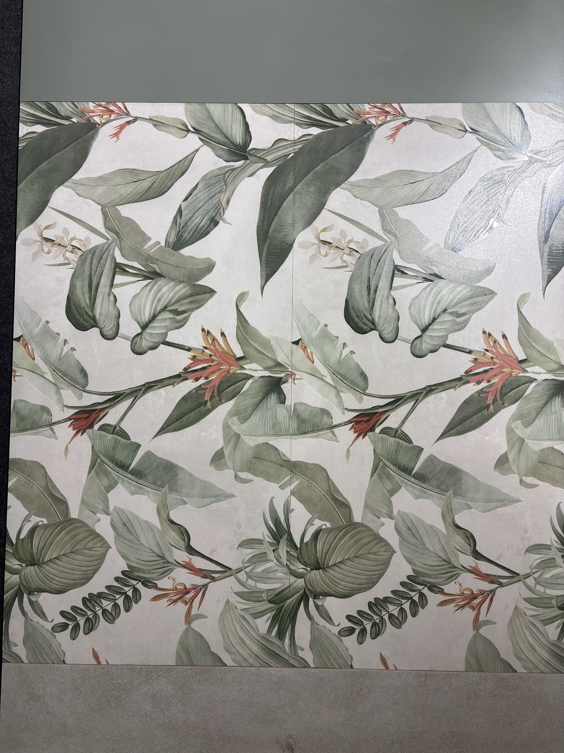 Botanical decorative tile panel with green leaves and orange flowers photographed in the showroom