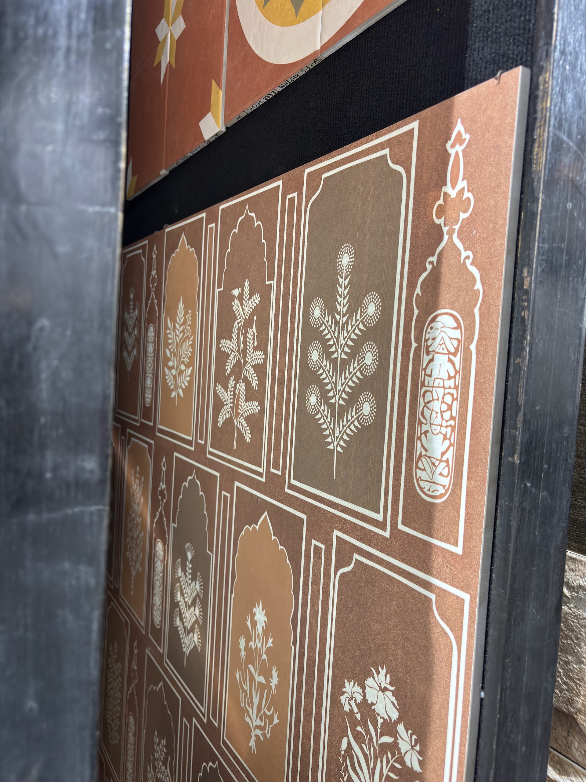 Terracotta tone tiles with white floral motifs inside arched frames at the World of Tile showroom