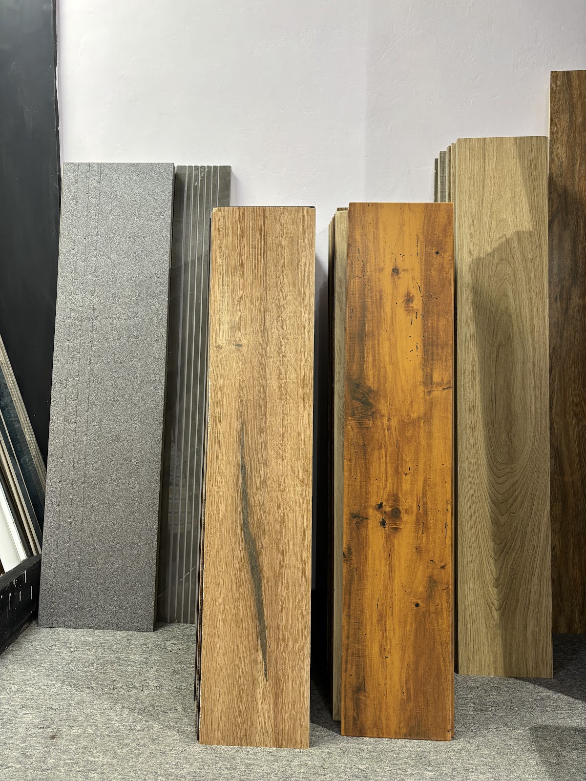 Wood finish tile planks beside grey textured tile samples at World of Tile in Noida