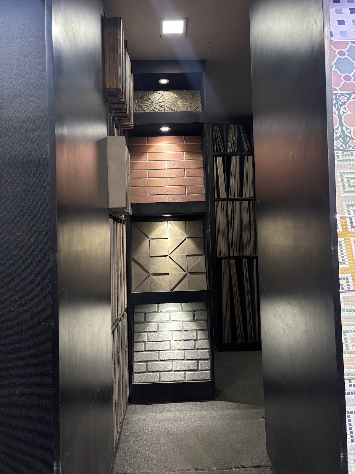 Illuminated corridor of textured wall displays at the World of Tile showroom in Sector 9 Noida